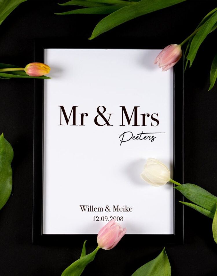 Bovenaanzicht van een gepersonaliseerde huwelijksposter met de tekst 'Mr & Mrs Peeters', de namen Willem & Meike en hun trouwdatum, in een zwarte lijst omringd door roze en witte tulpen op een zwarte achtergrond.