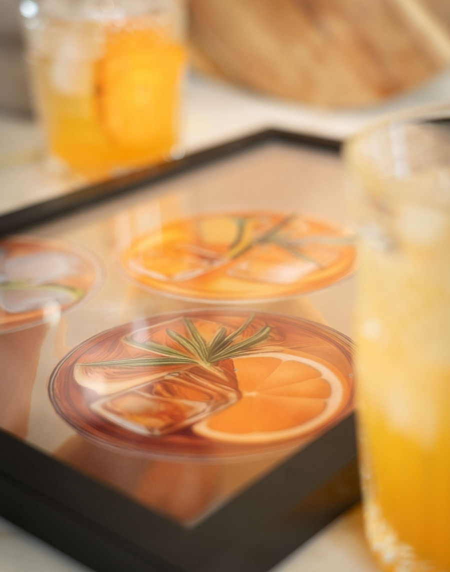 Sfeervolle schuine opname van een ingelijste poster met cocktail illustraties in zwarte lijst, met een glazen cocktail op de voorgrond.