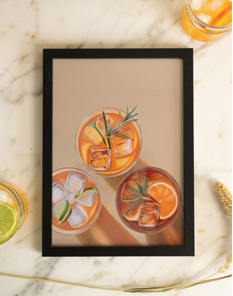 Bovenaanzicht van een ingelijste poster met geïllustreerde cocktails met ijsblokjes en fruit, geplaatst in een zwarte fotolijst op een marmeren ondergrond.
