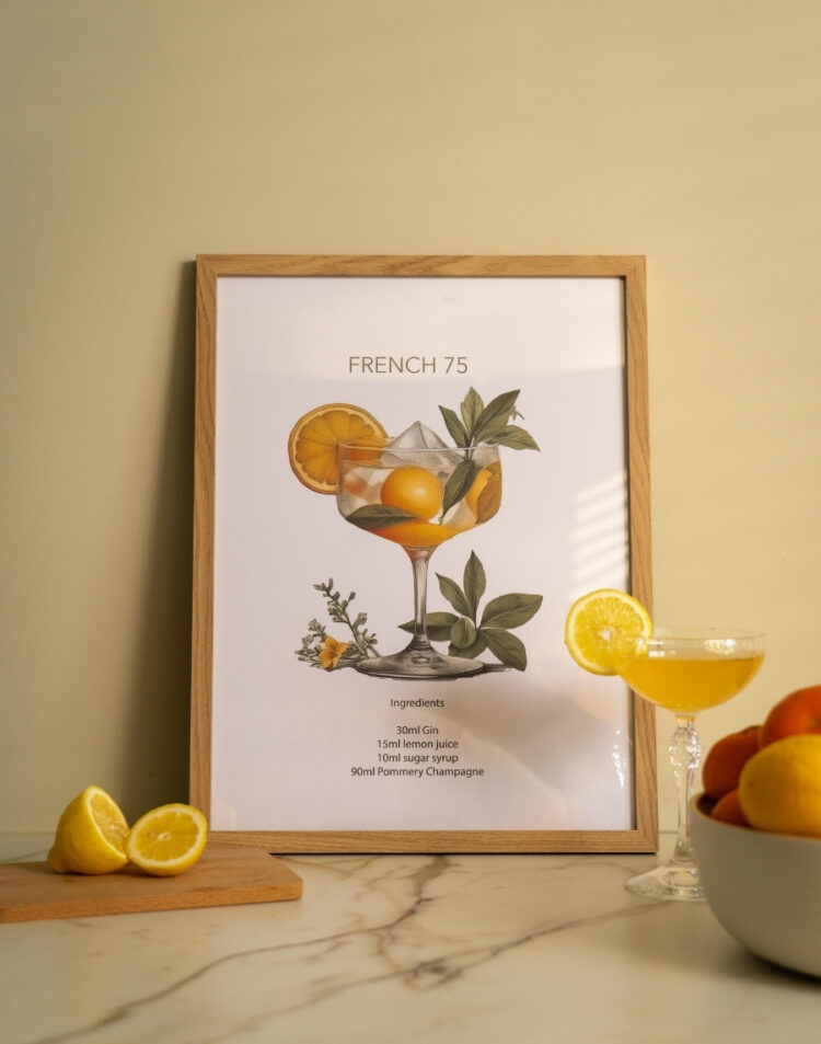 Ingelijste cocktail poster van een French 75 met illustratie en ingrediënten recept, staand op een marmeren aanrecht naast een glas cocktail en verse citroenen.