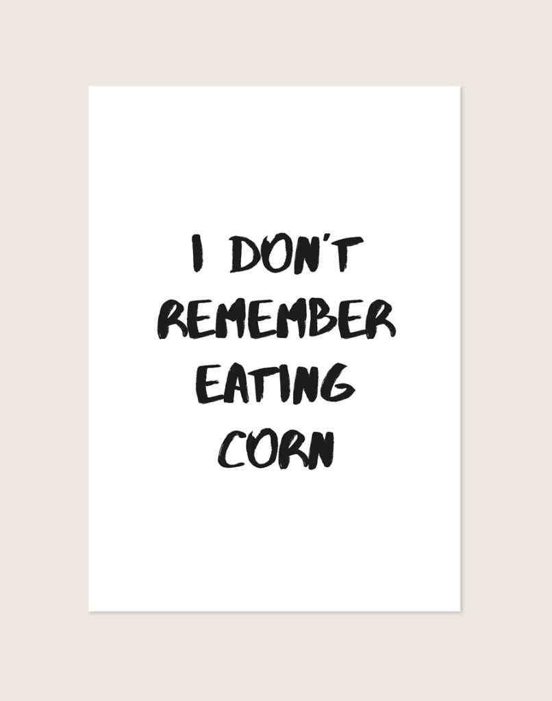 Minimalistische zwart-witte Corn poster met de tekst I DON'T REMEMBER EATING CORN in stoere brush-letters, sfeervol opgehangen in een toiletruimte.