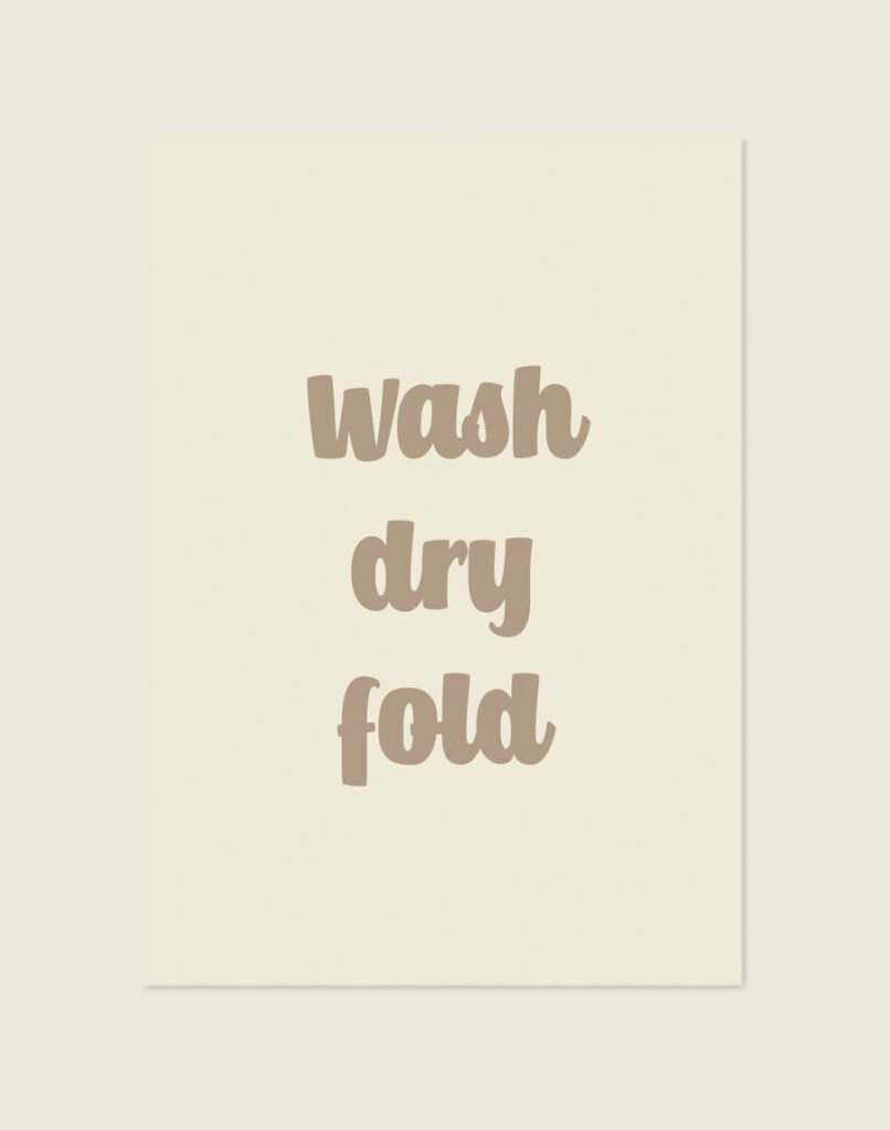 Sfeervolle crèmekleurige Fold poster met taupebruine letters en de tekst wash dry fold, sfeervol opgehangen in een stijlvolle wasruimte.