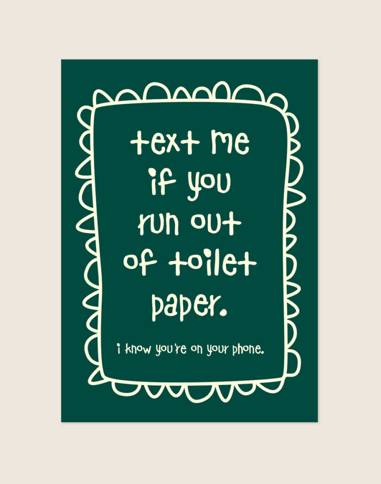 Diep donkergroene poster met crèmekleurige handgeschreven tekst text me if you run out of toilet paper en een gegolfde rand, sfeervol opgehangen aan een neutrale muur in een moderne toiletruimte.
