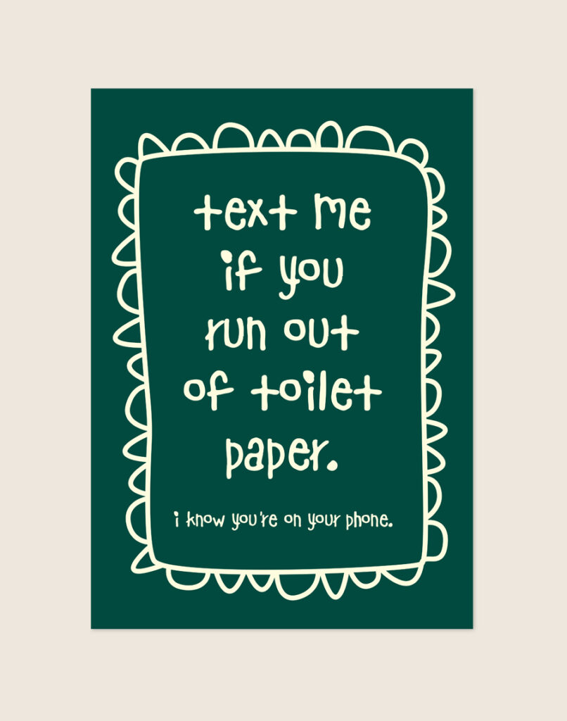 Diep donkergroene poster met crèmekleurige handgeschreven tekst text me if you run out of toilet paper en een gegolfde rand, sfeervol opgehangen aan een neutrale muur in een moderne toiletruimte.