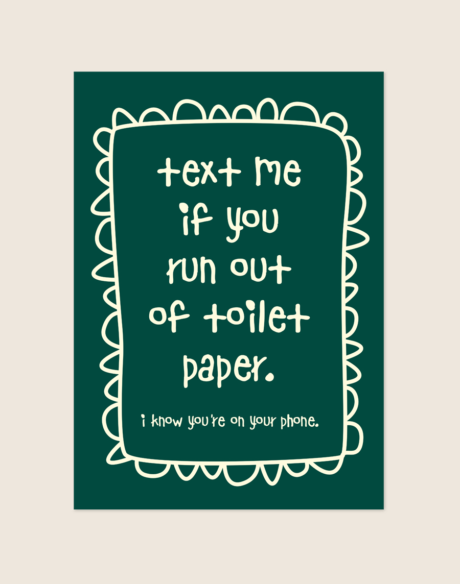 Diep donkergroene poster met crèmekleurige handgeschreven tekst text me if you run out of toilet paper en een gegolfde rand, sfeervol opgehangen aan een neutrale muur in een moderne toiletruimte.