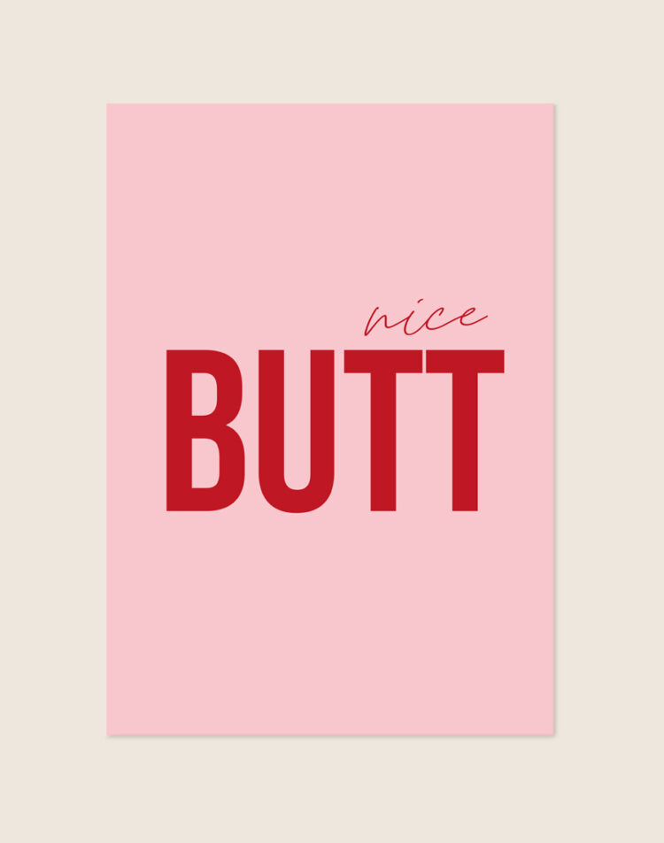 Trendy roze typografische poster met rode tekst nice BUTT, sfeervol opgehangen aan een neutrale muur in een moderne toiletruimte.