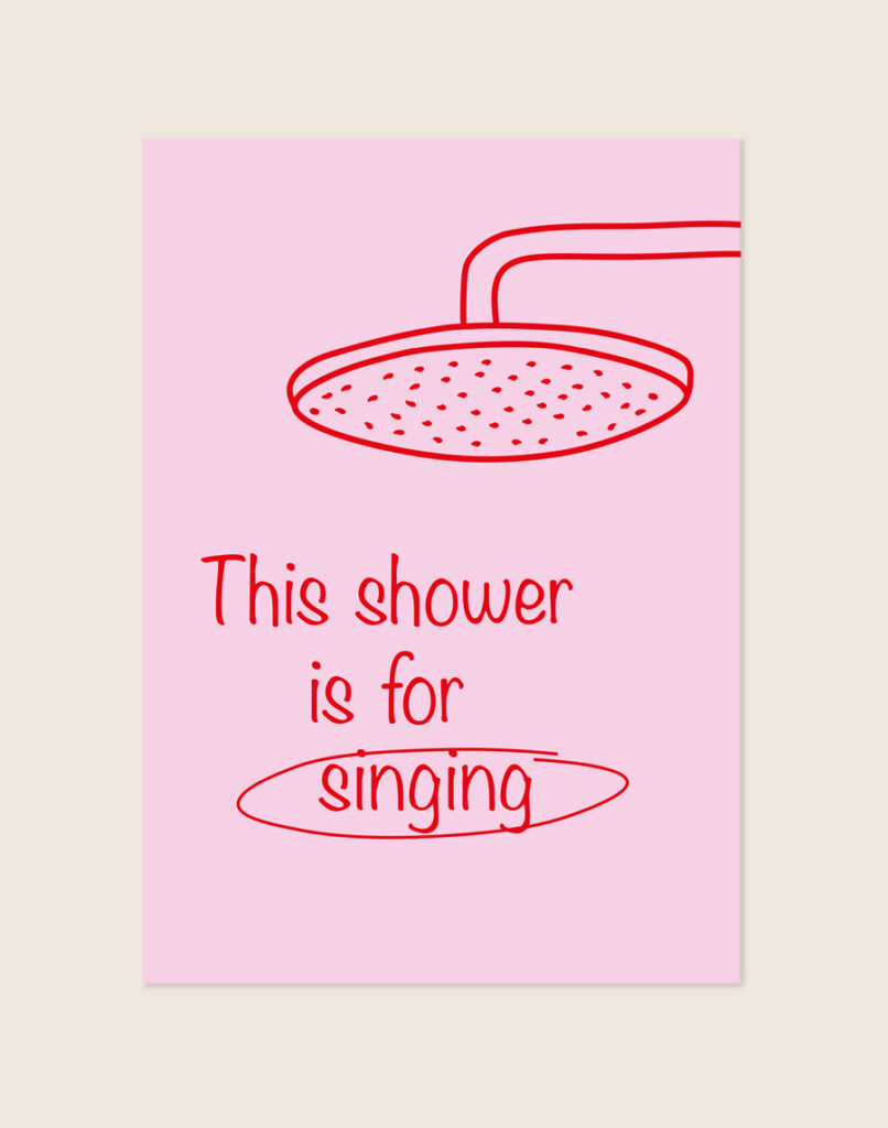 Vrolijke roze poster met een rode douchekop illustratie en de tekst This shower is for singing, sfeervol opgehangen aan een neutrale muur in een moderne badkamer.