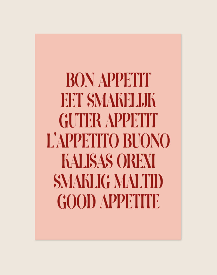 Stijlvolle typografische poster met het woord Smakelijk, sfeervol opgehangen aan een neutrale muur boven de eettafel in een moderne eetkamer.
