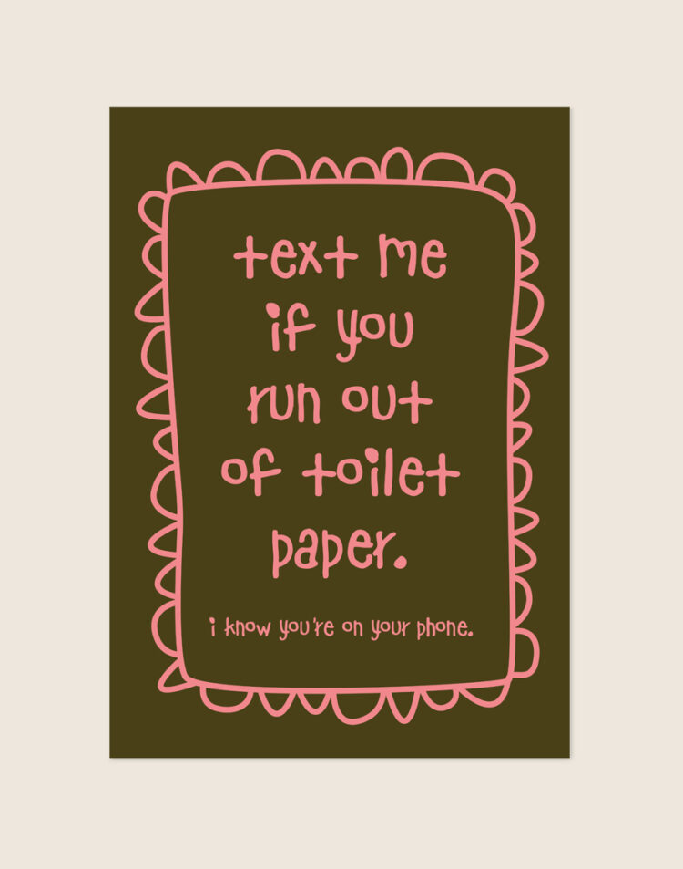 Warme diepbruine poster met roze handgeschreven tekst text me if you run out of toilet paper i know you're on your phone en een gegolfde rand, sfeervol opgehangen aan een neutrale muur in een moderne toiletruimte.