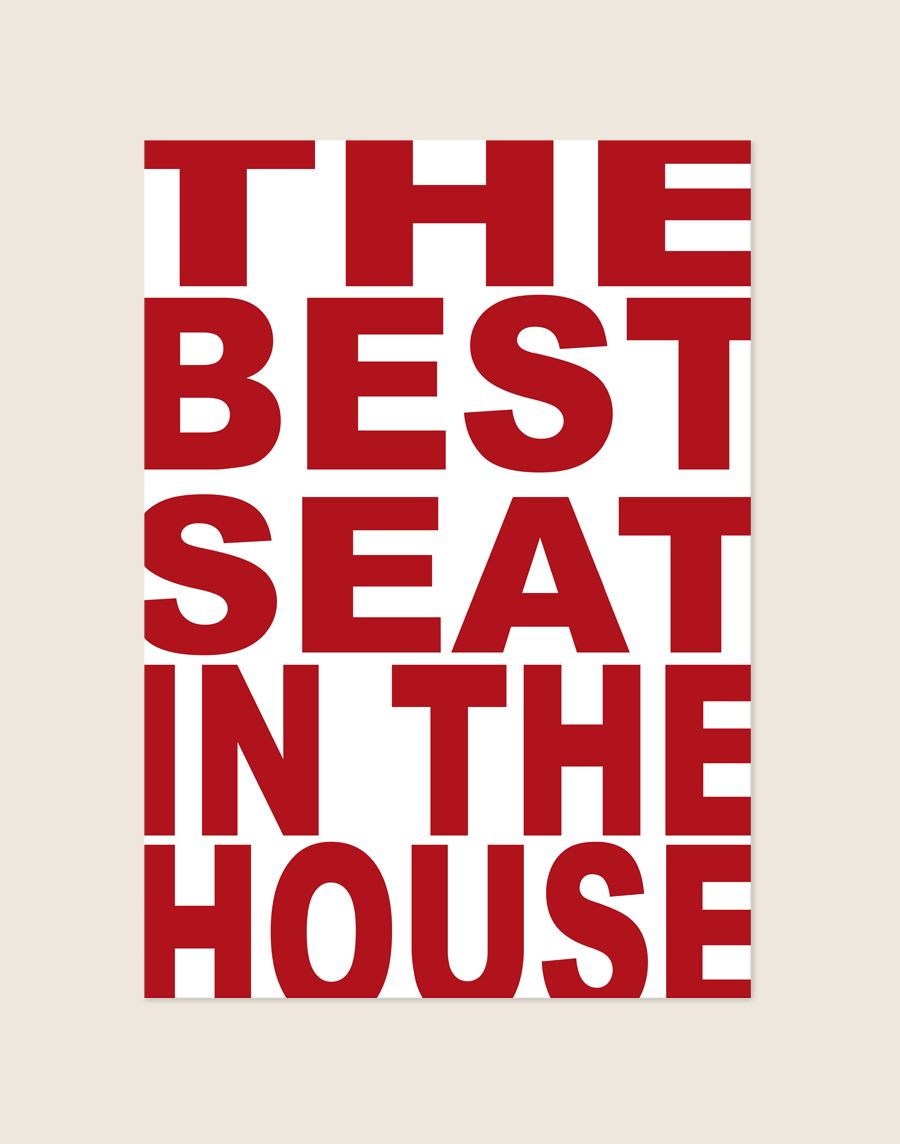 Opvallende witte poster met grote rode blokletters en de tekst The Best Seat In The House, sfeervol opgehangen aan een neutrale muur in een moderne toiletruimte.