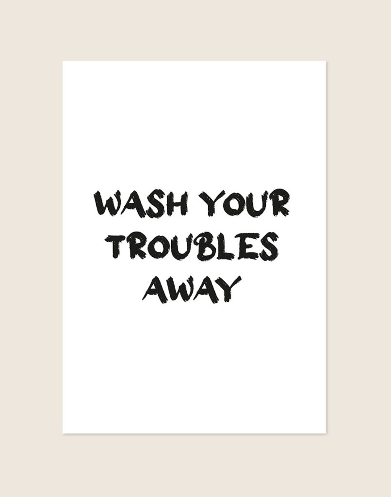 Rustgevende badkamer Poster Wash troubles away met de Engelse quote in zwarte kwaststreken op een helderwitte achtergrond, sfeervol opgehangen in een ruimte.