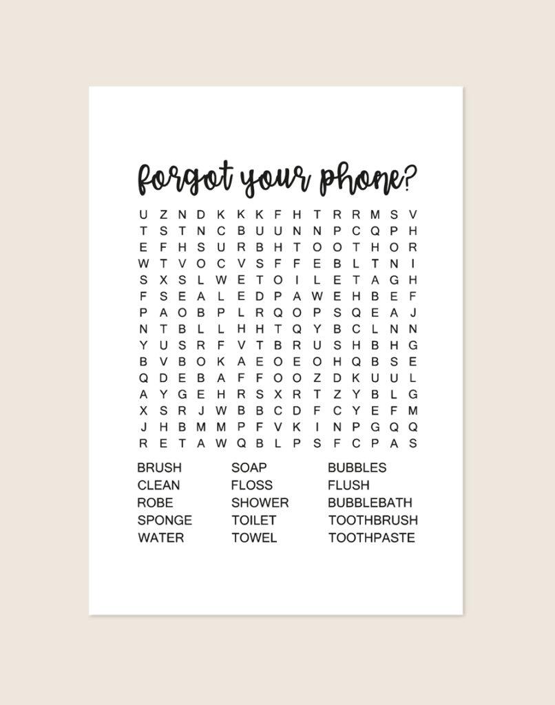 Minimalistische zwart-witte poster met een zwarte woordzoeker en de tekst forgot your phone?, sfeervol opgehangen aan een neutrale muur in een moderne toiletruimte.