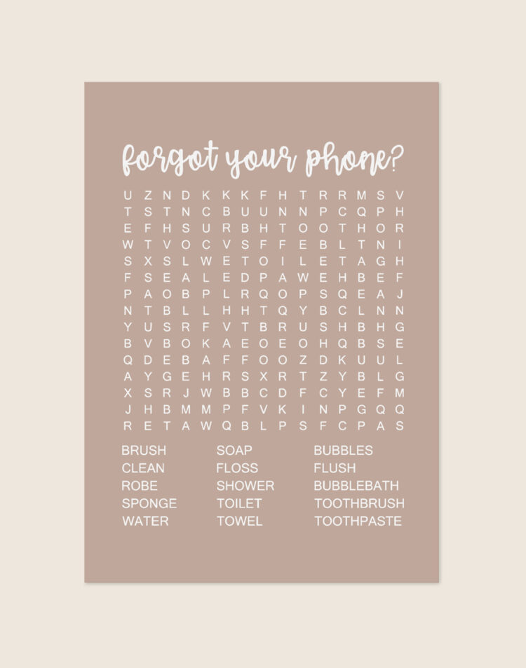 Warme zandbeige poster met een witte woordzoeker en de tekst forgot your phone?, sfeervol opgehangen aan een neutrale muur in een moderne toiletruimte.