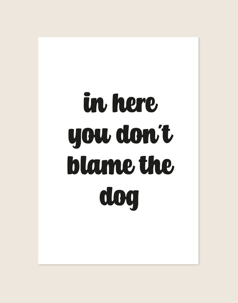 Humoristische WC Poster Blame the dog met de Engelse quote "in here you don't blame the dog" in zwarte afgeronde letters op een helderwitte achtergrond, sfeervol opgehangen in een ruimte.