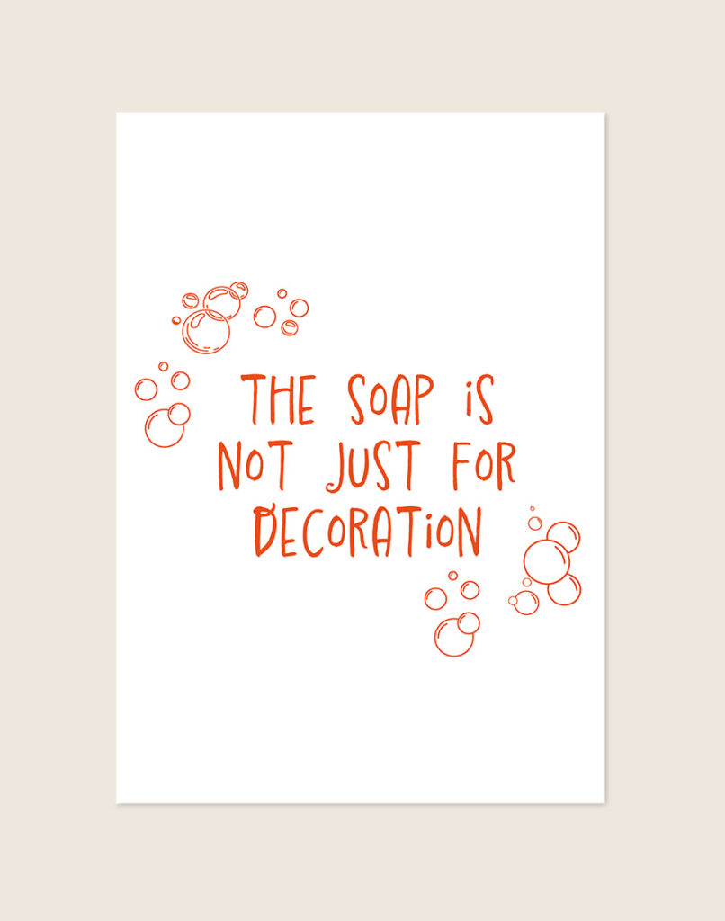 Humoristische badkamer Poster Decoration met de oranje tekst "The soap is not just for decoration" en speelse zeepbellen op een helderwitte achtergrond, sfeervol opgehangen in een ruimte.