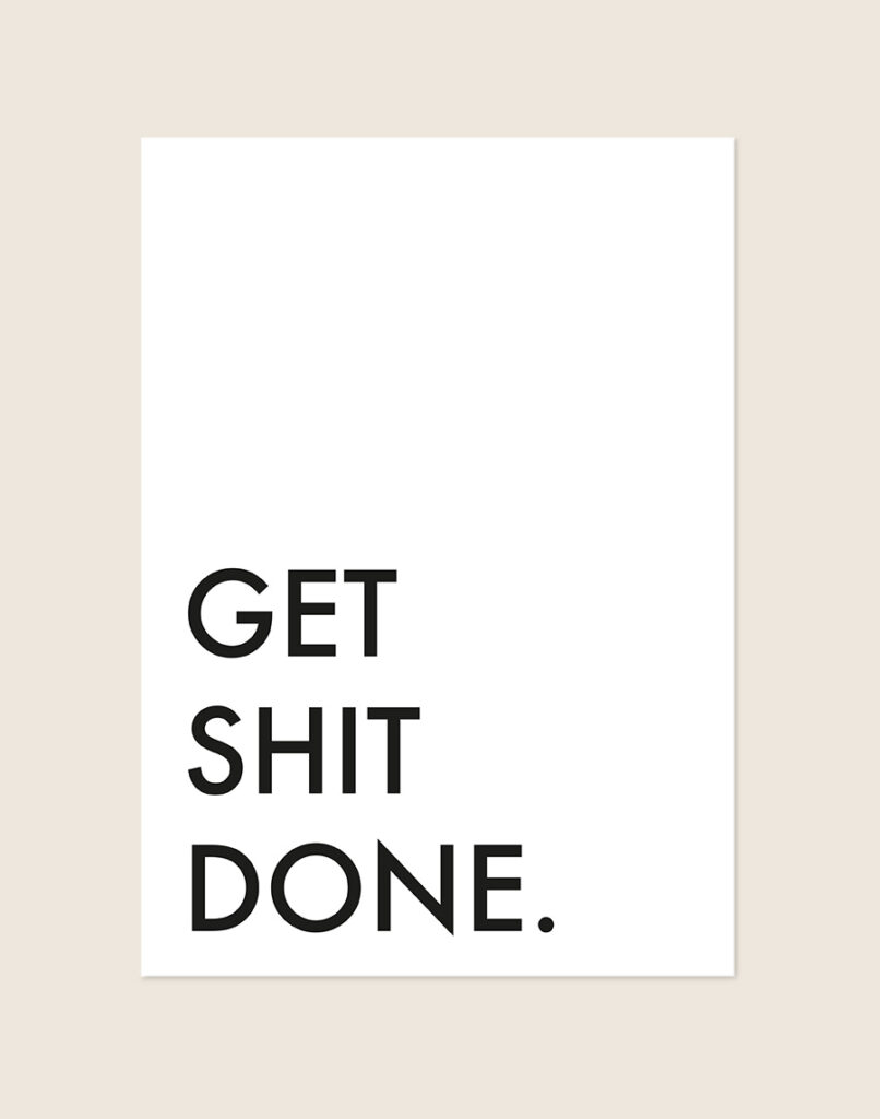 Minimalistische Poster Get shit done met strakke zwarte letters en veel witruimte op een helderwitte achtergrond, sfeervol opgehangen in een ruimte.