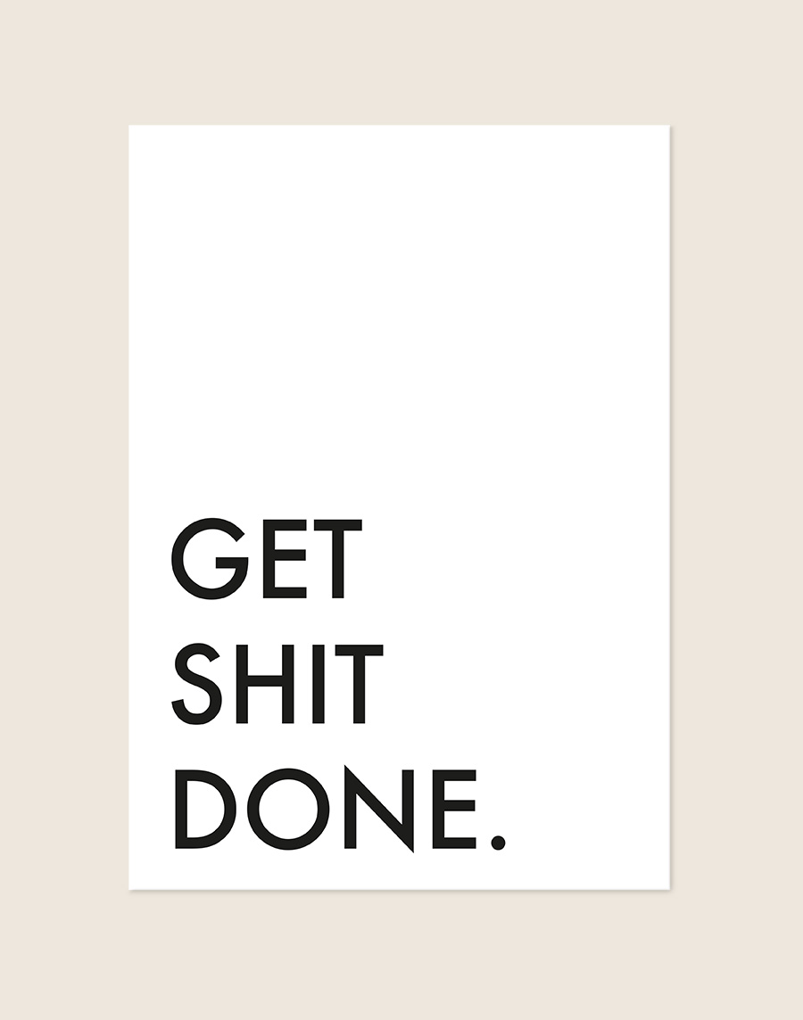 Minimalistische Poster Get shit done met strakke zwarte letters en veel witruimte op een helderwitte achtergrond, sfeervol opgehangen in een ruimte.