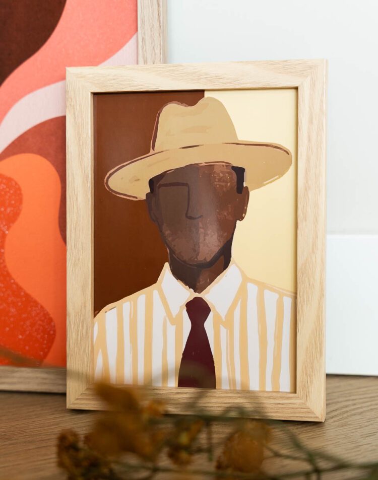 Een houten schilderijlijst met een artistieke illustratie van een man met een hoed, gestreept overhemd en een donkere stropdas. Het portret is opgebouwd uit aardetinten zoals bruin, beige en geel. Op de achtergrond is een gedeelte van een andere kleurrijke poster te zien.